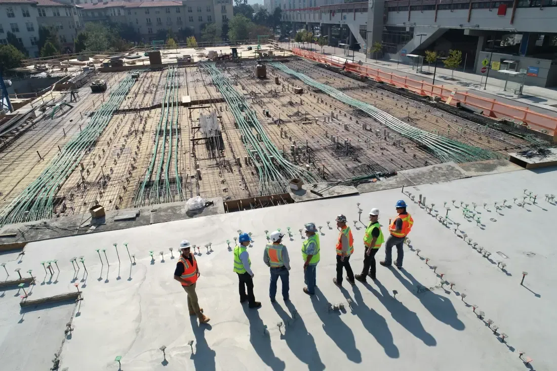 Construction crew on a structural steel rooftop deck overseeing a large commercial project